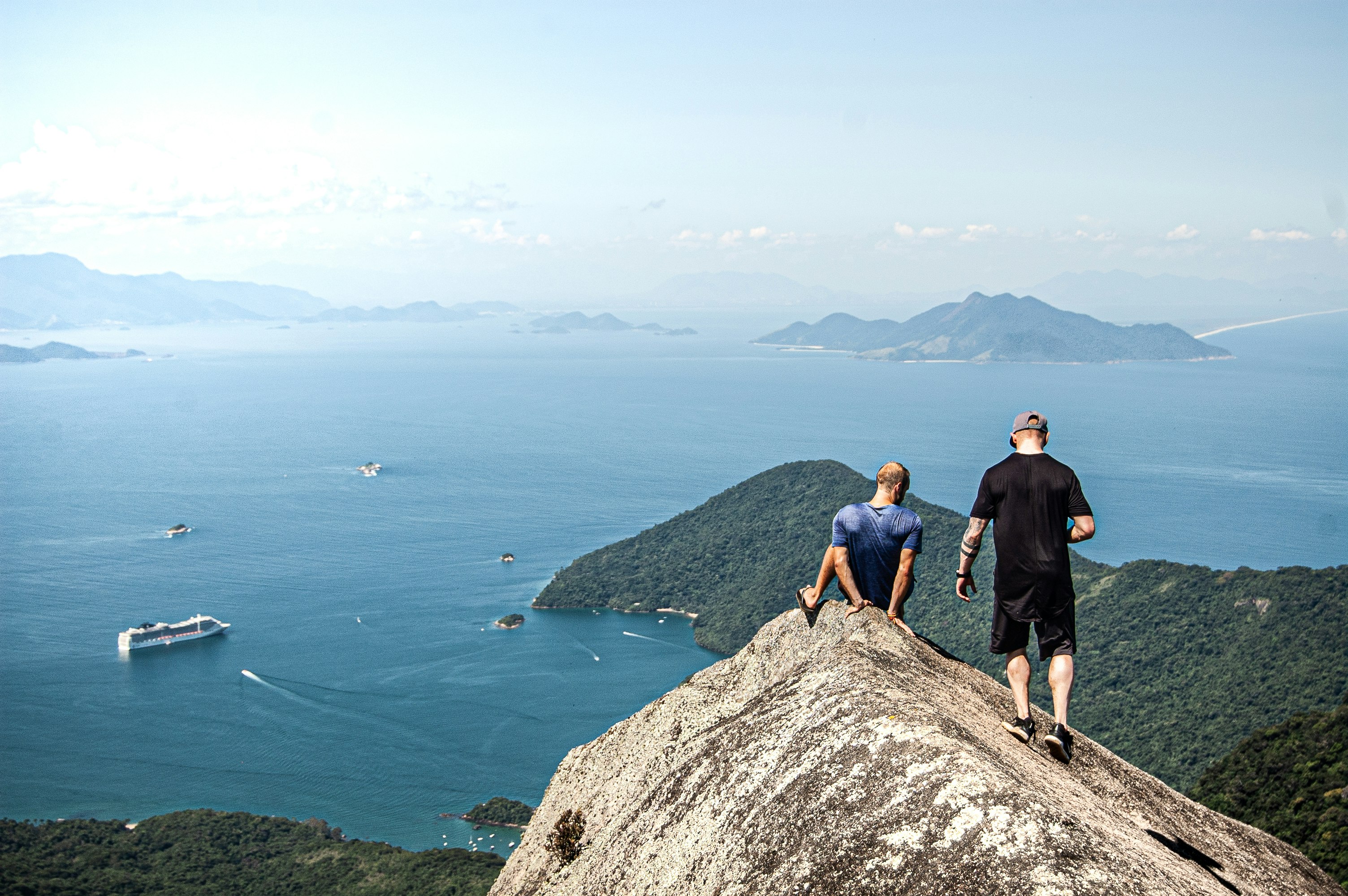 man in black shirt standing on rock formation near body of water during daytime